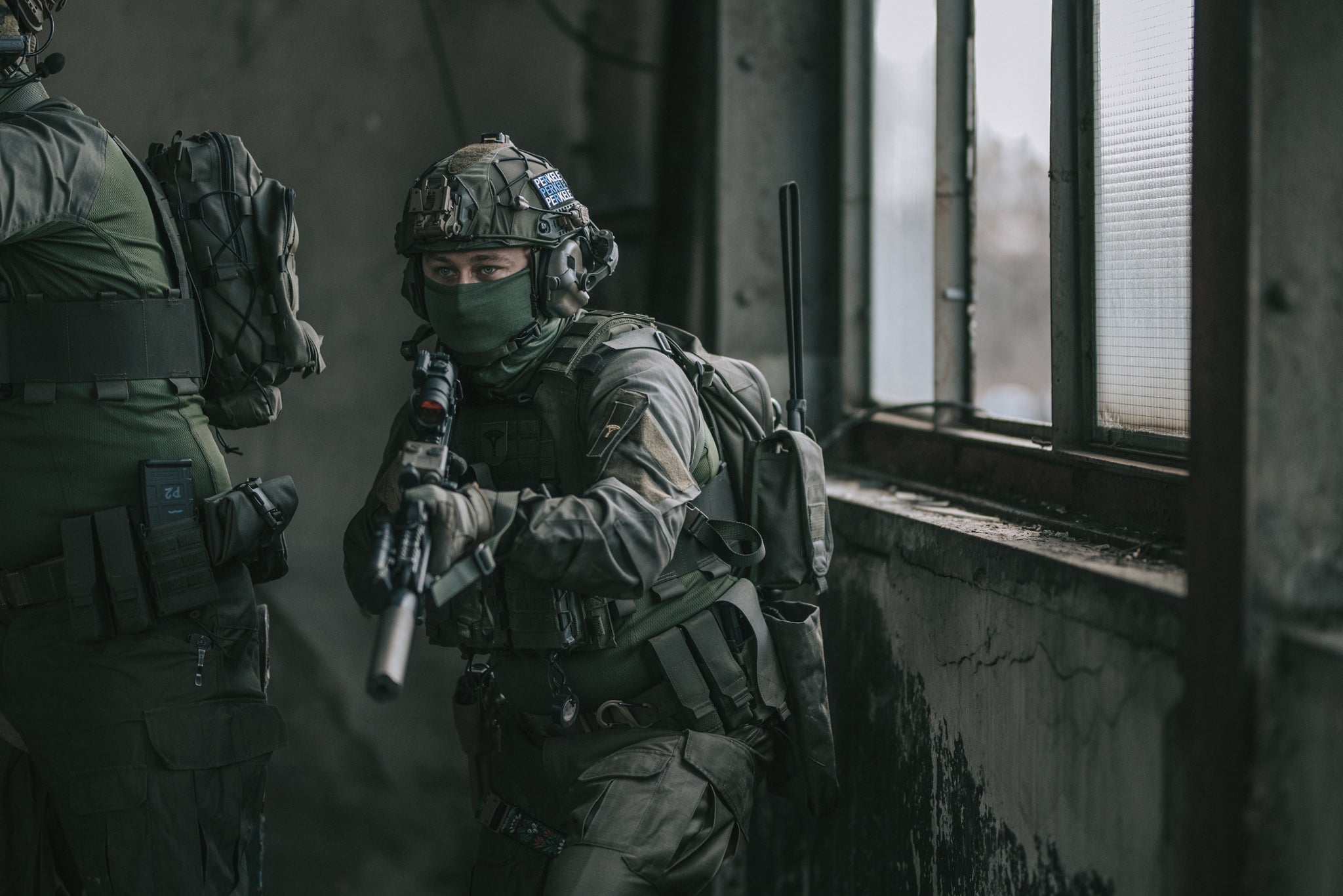 Person in tactical gear with a rifle in an indoor setting