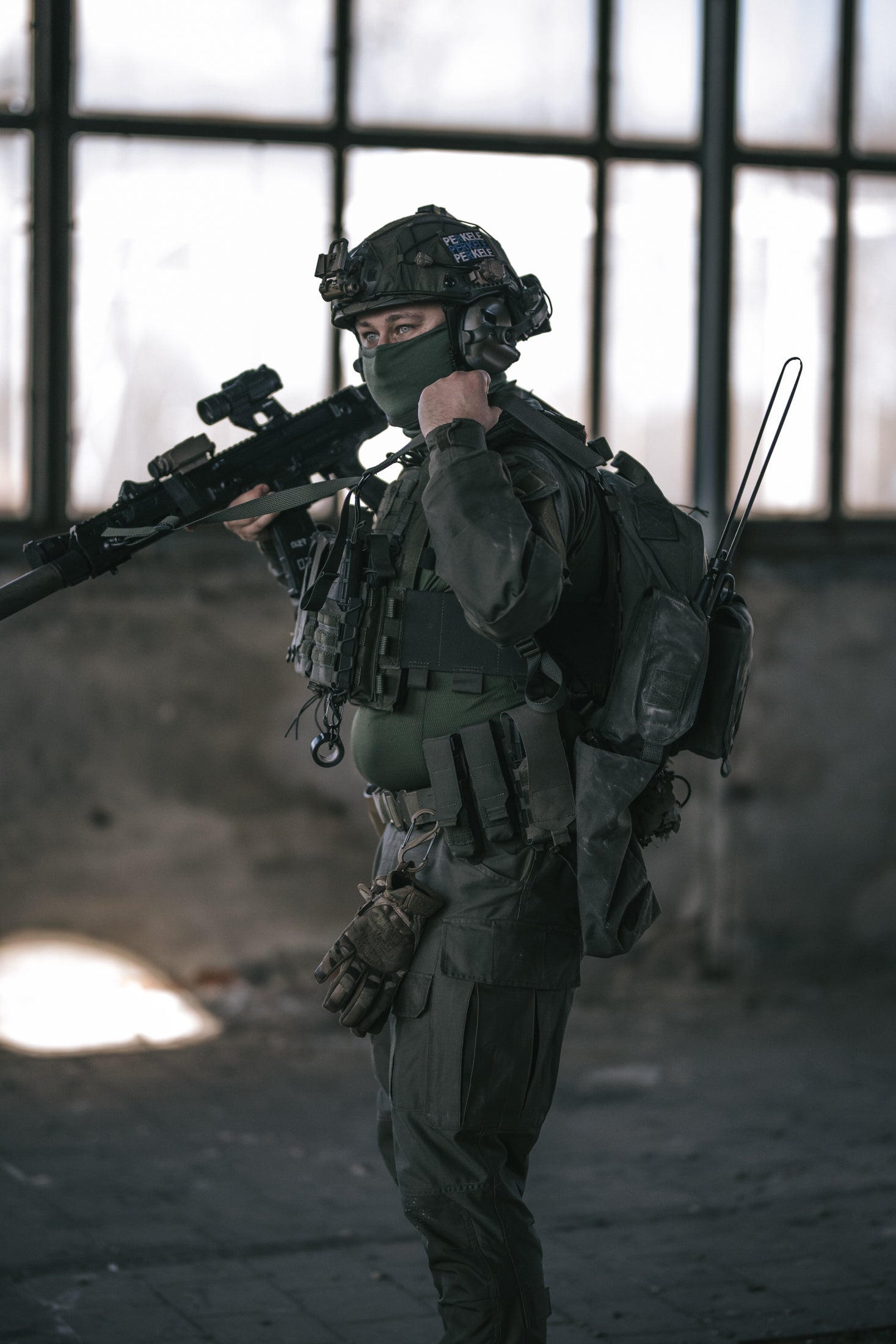 Person in tactical gear holding a rifle in an industrial setting