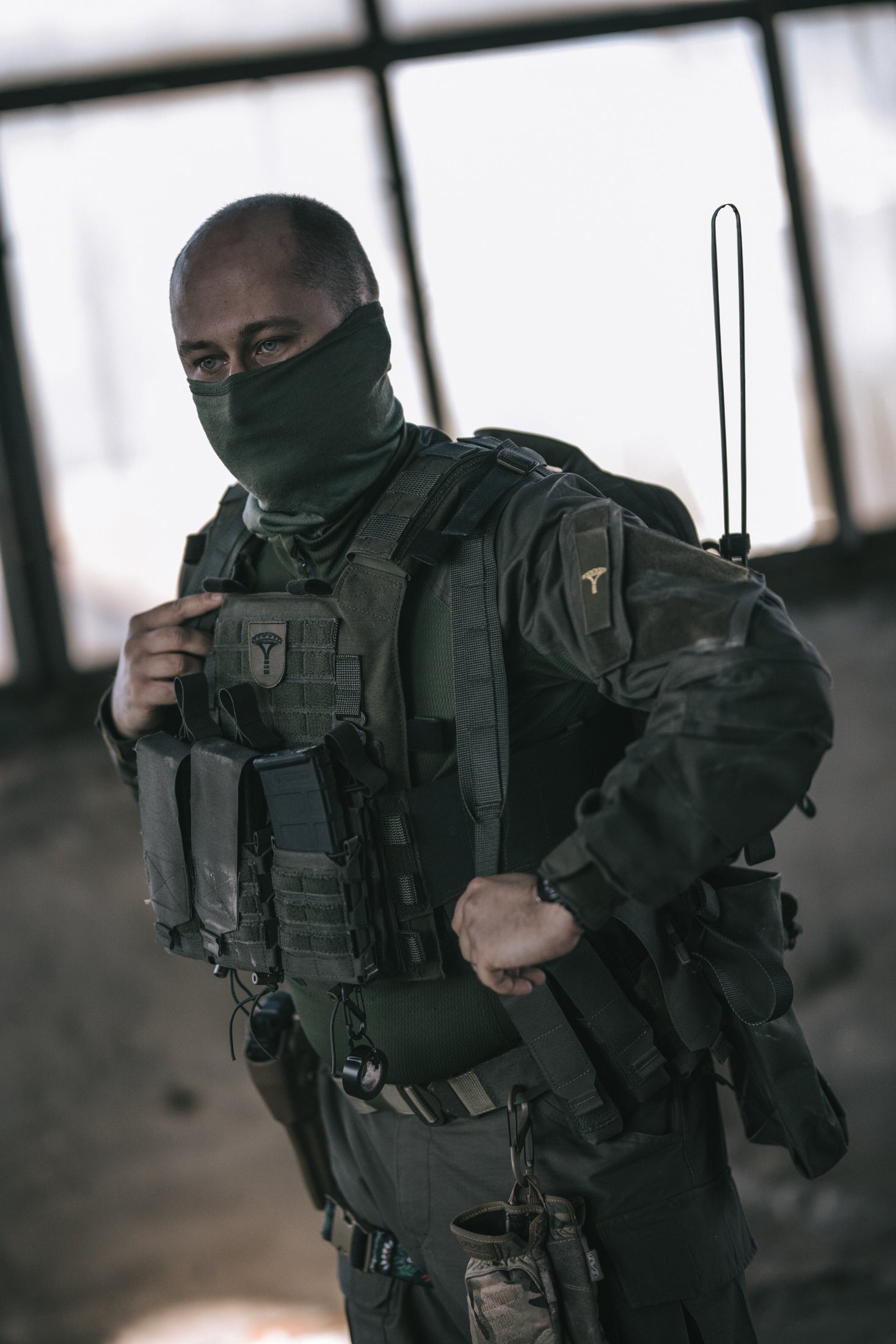 Person in tactical gear with a blurred background adjusting the strap of his backpack