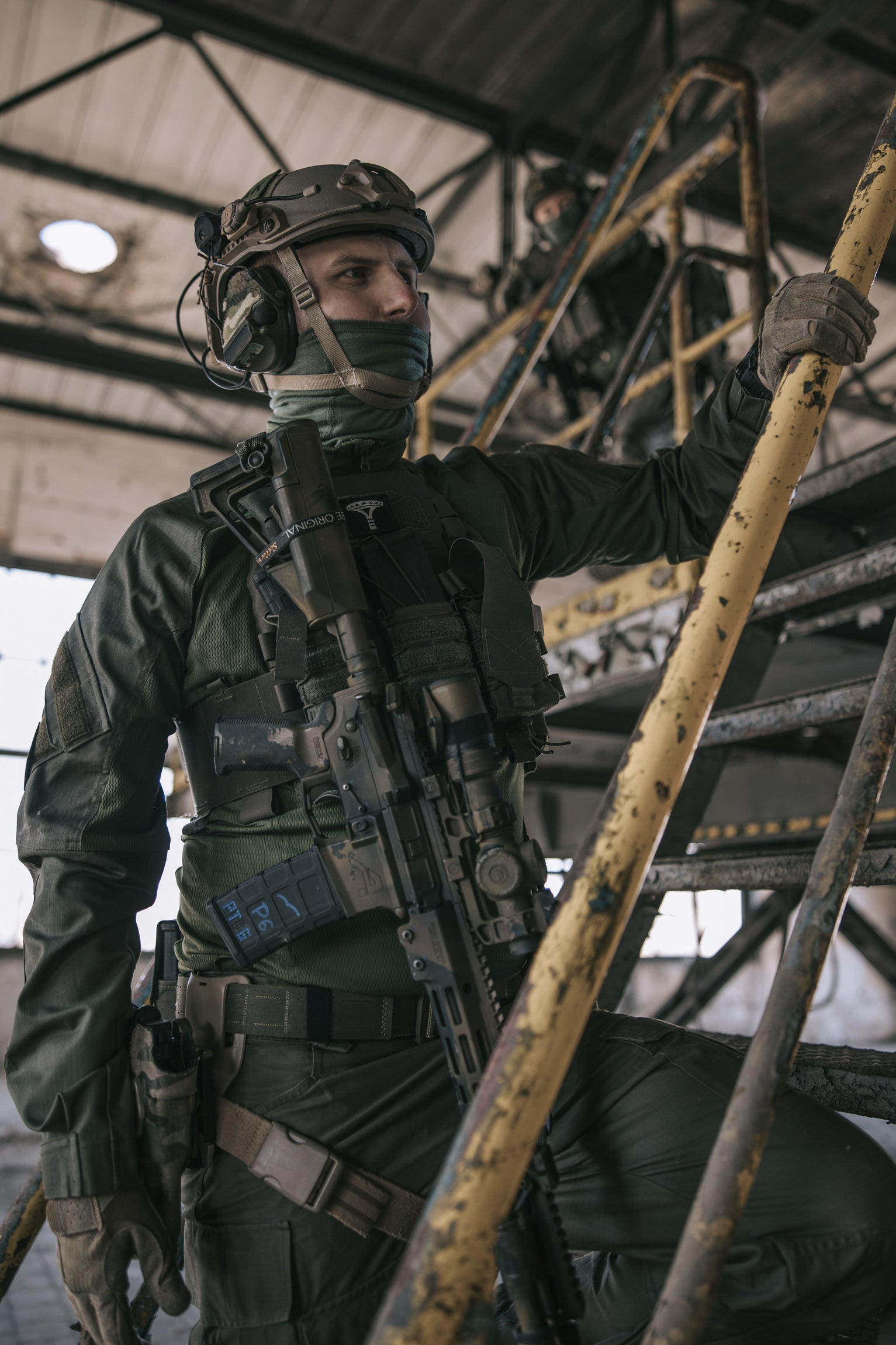 Person in tactical gear standing on the stairs in an industrial setting
