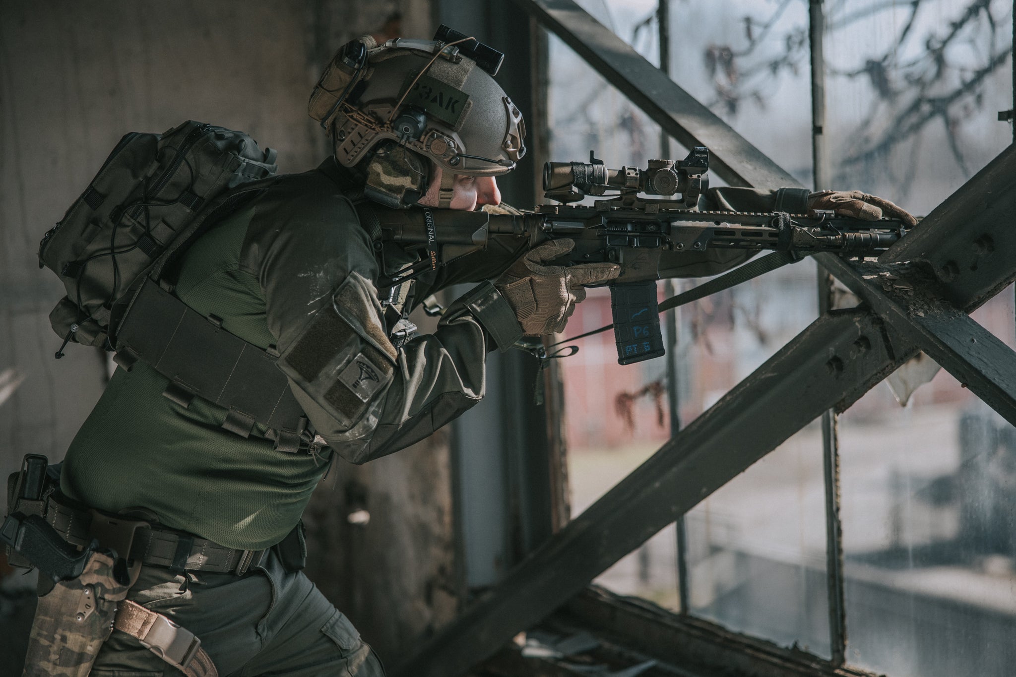 Person in tactical gear with a rifle in an urban setting