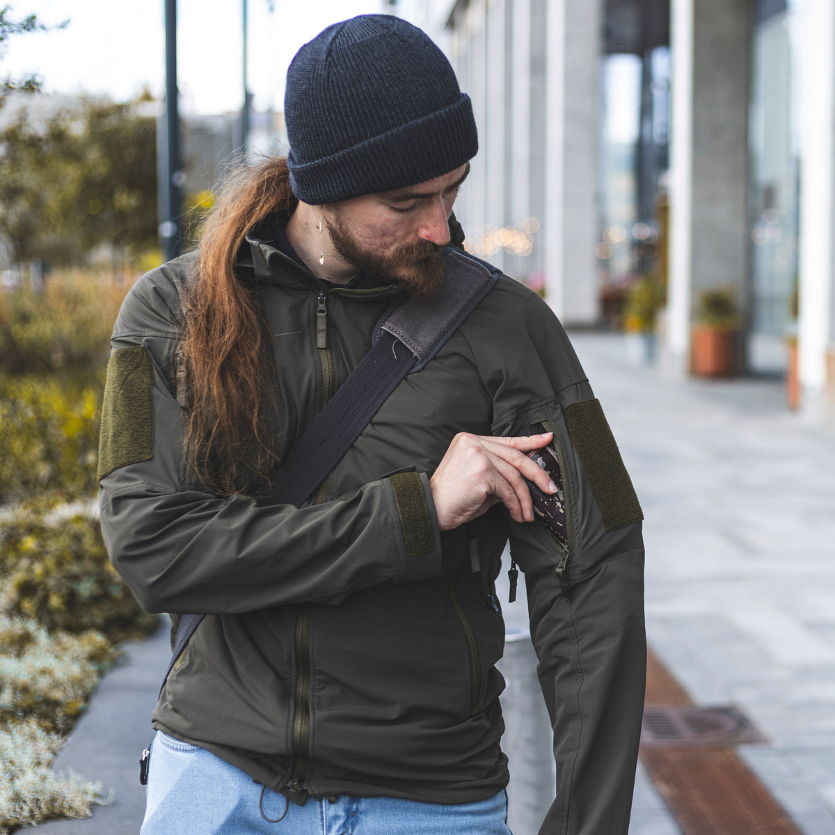 Ranger Green Varusteleka L3 softshell jacket with sleeve pockets, velcro patches, and a high collar worn outdoors.