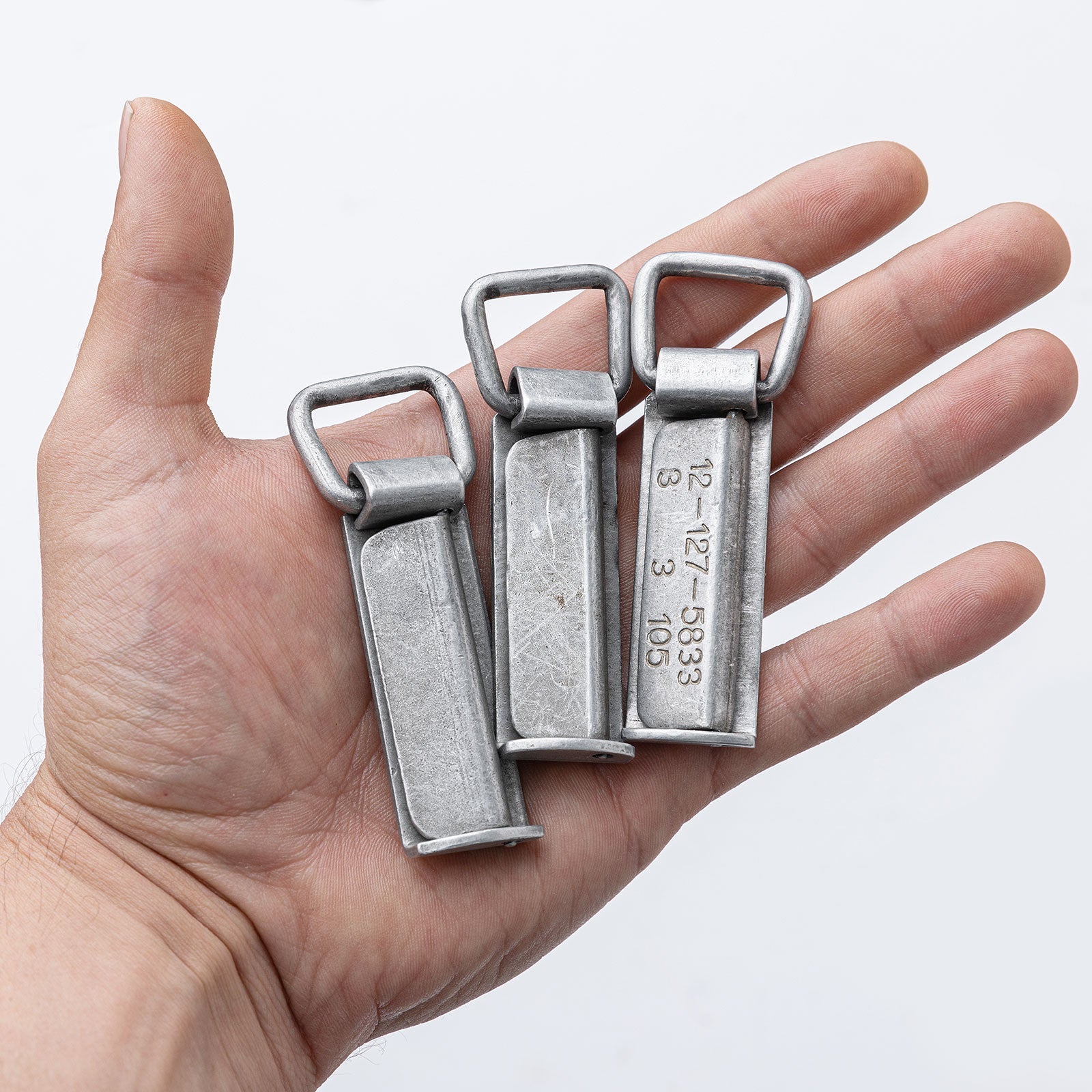 Three aluminum Bundeswehr belt clips on an open palm