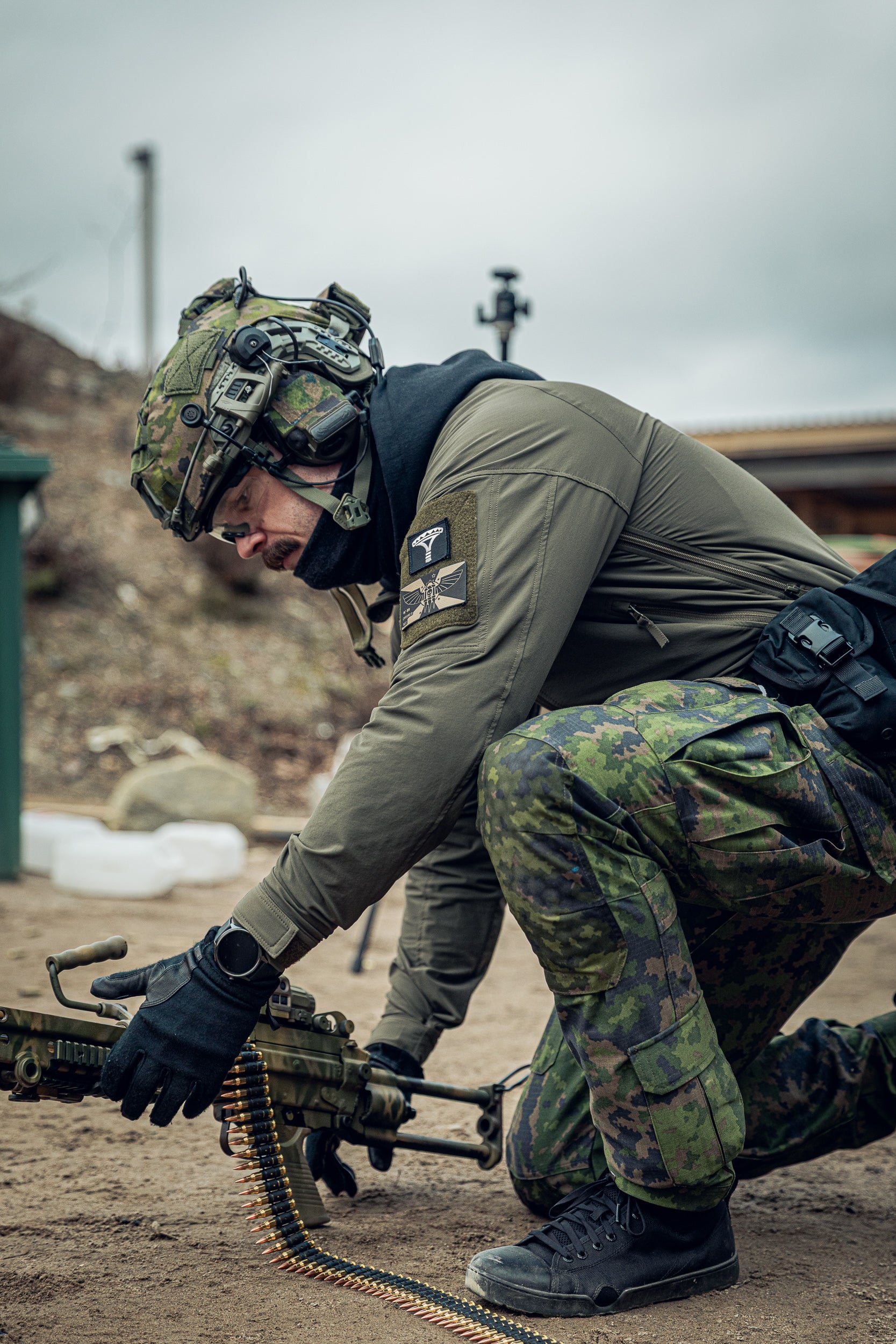 Person in military gear with a rifle  kneeling down and reloading the rigle.