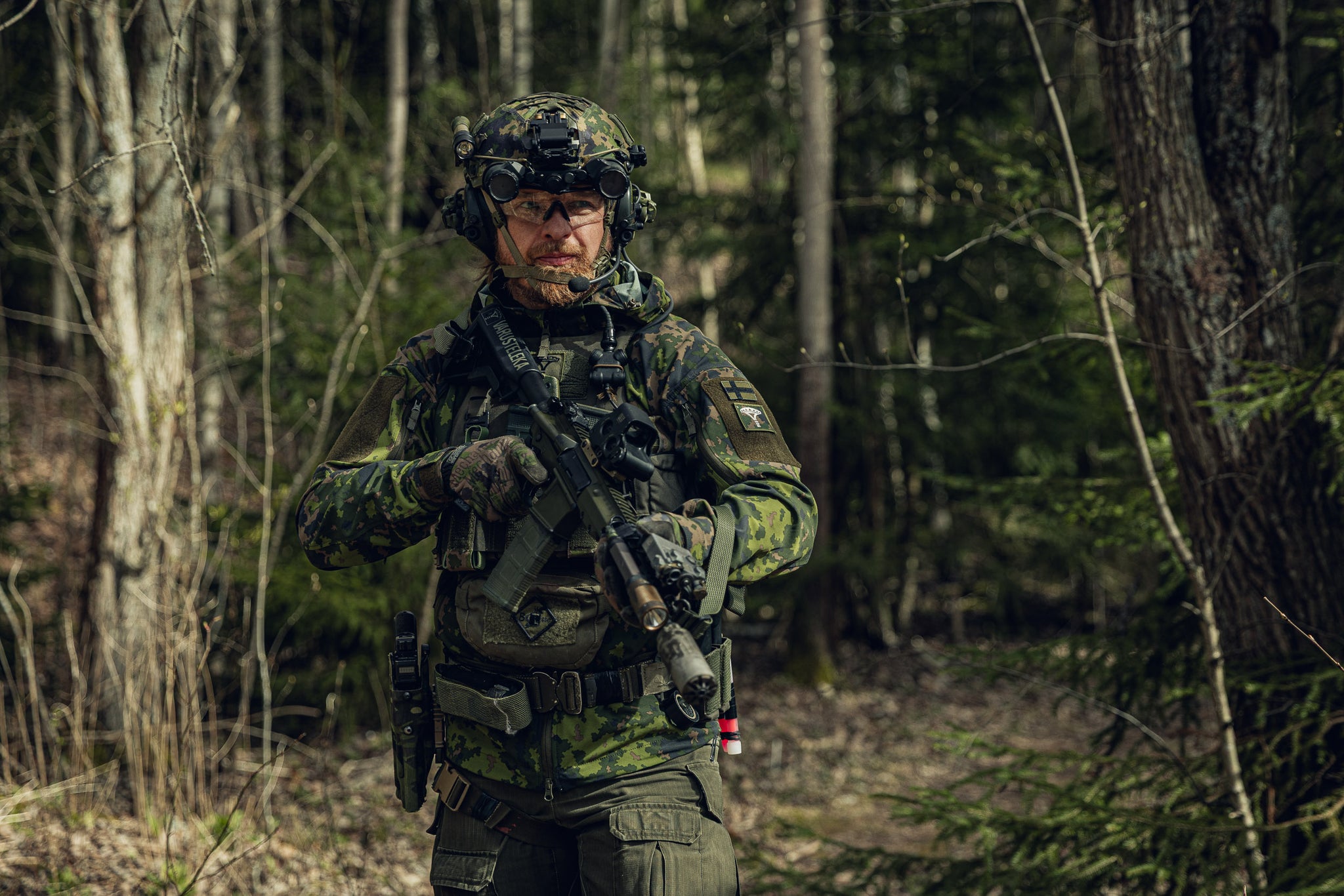 Person in camouflage gear with a rifle in a forest setting