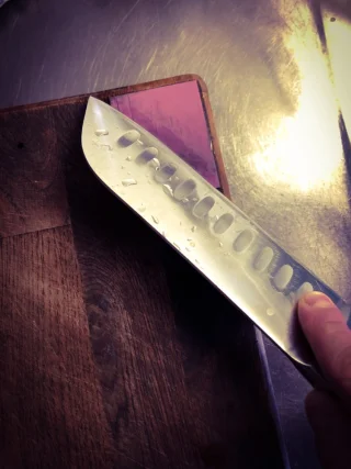 Glue it to the corner of your cutting board: you'll use it more frequently when it's easy.